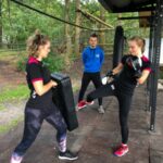 2 vrouwen doen de activiteit boksfit onder begeleiding van een instructeur