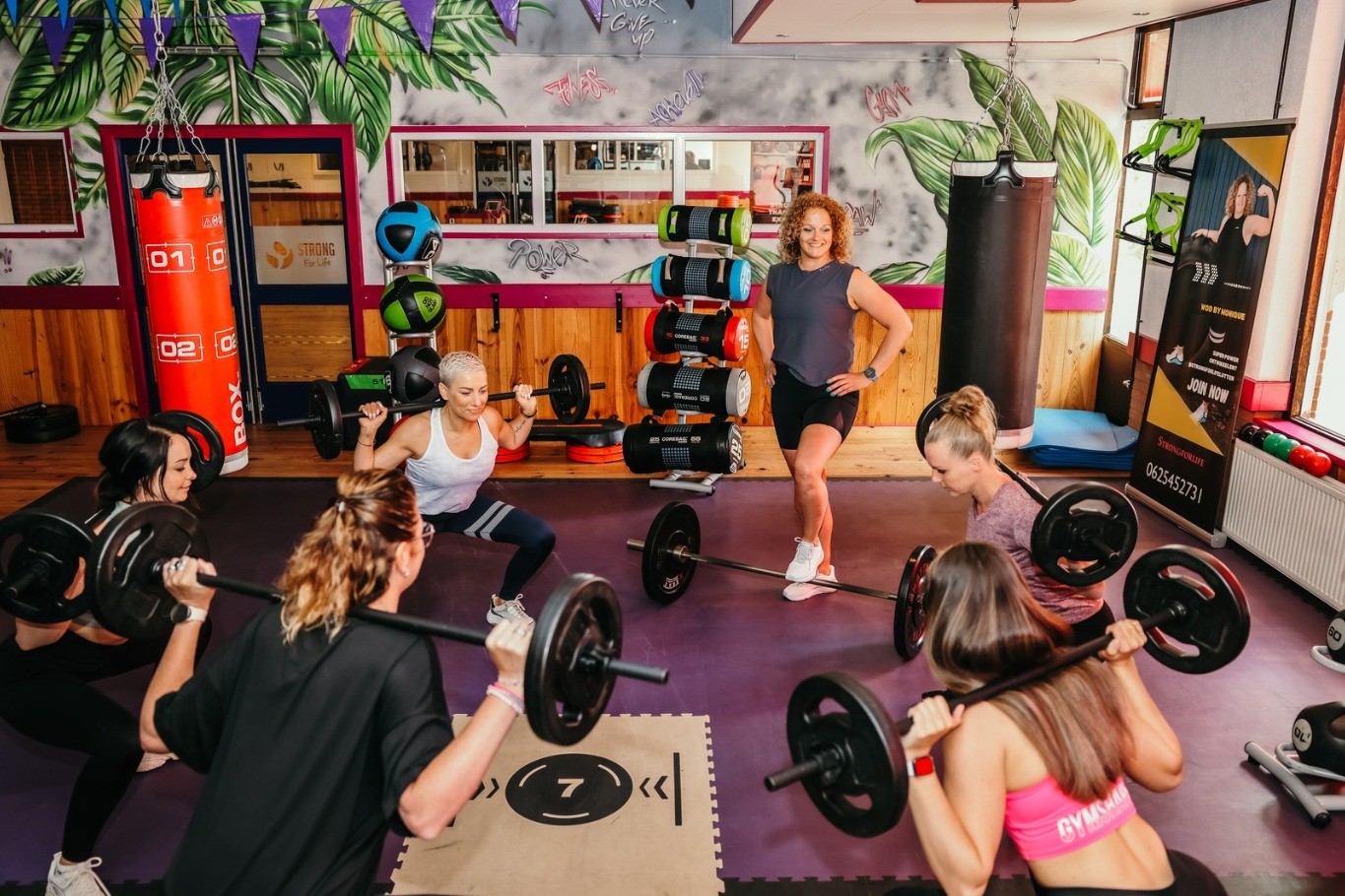 Een groep sporters is bezig met een workout met haltergewichten onder leiding van sportinstructeur