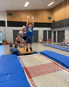 Kinderen springen op grote dubbele trampoline in gymzaal