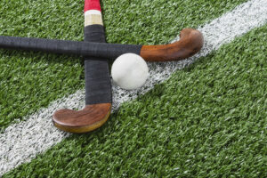 Kijkend naar een paar hockeysticks met een bal op de middenlijn