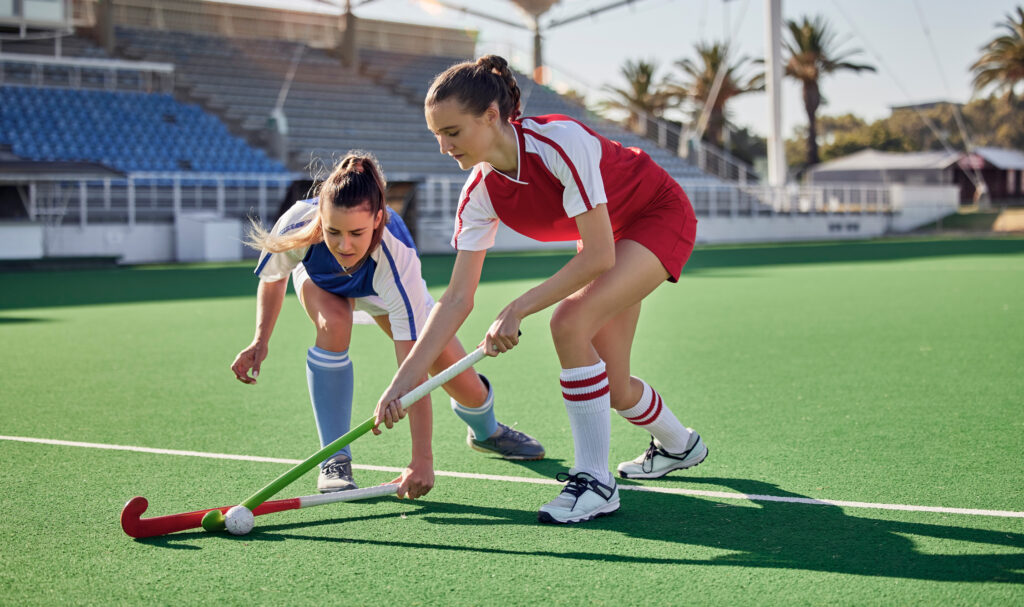 Twee hockey spelende vrouwen op kunstgras