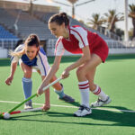 Twee hockey spelende vrouwen op kunstgras