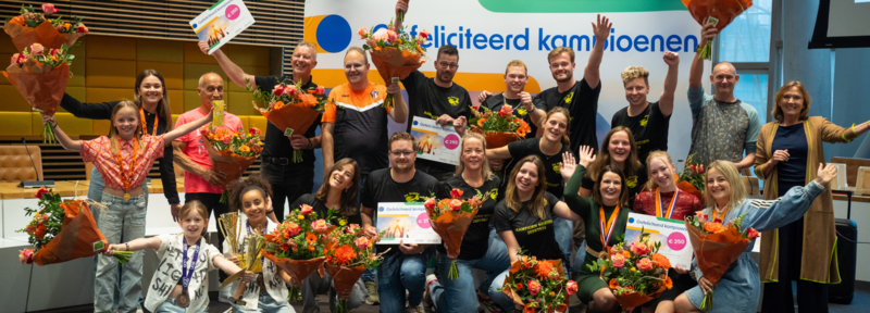 Groepsfoto van meerdere mensen die sportkampioen zijn geworden en zijn gehuldigd met een bos bloemen.