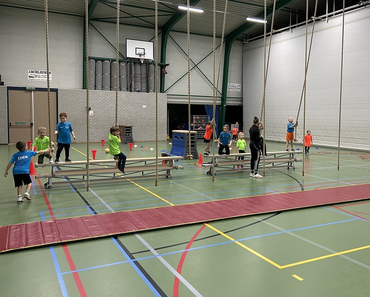 Meerdere kinderen die aan touwen zwaaien in een gymzaal