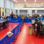 Meerdere rolstoeltafeltennisers spelen wedstrijd tafeltennis met scheidsrechters en scorebord