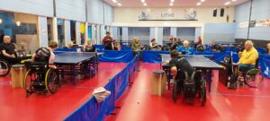 Meerdere rolstoeltafeltennisers spelen wedstrijd tafeltennis met scheidsrechters en scorebord