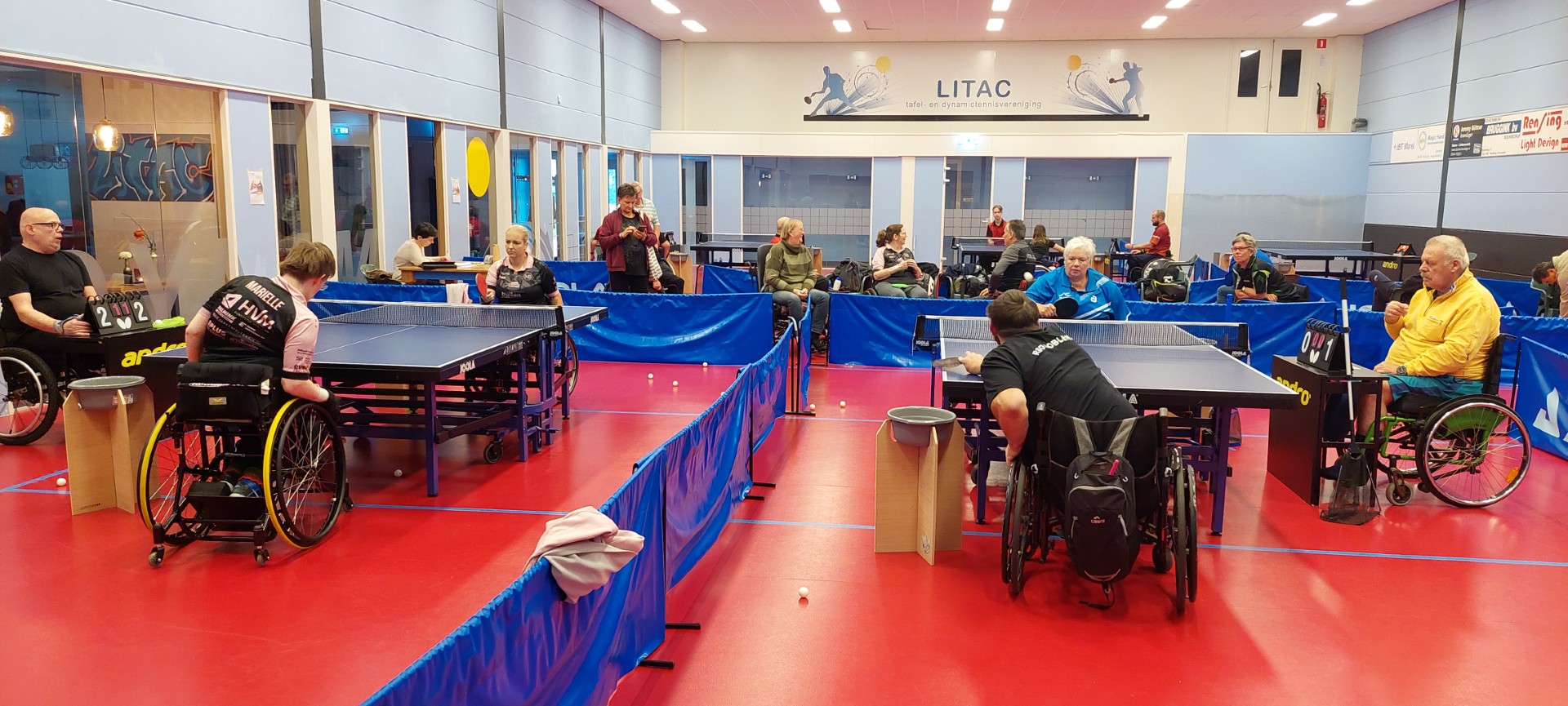 Meerdere rolstoeltafeltennisers spelen wedstrijd tafeltennis met scheidsrechters en scorebord