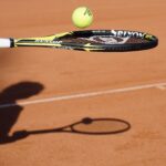 Tennisracket en tennisbal en schaduw van tennisspeler