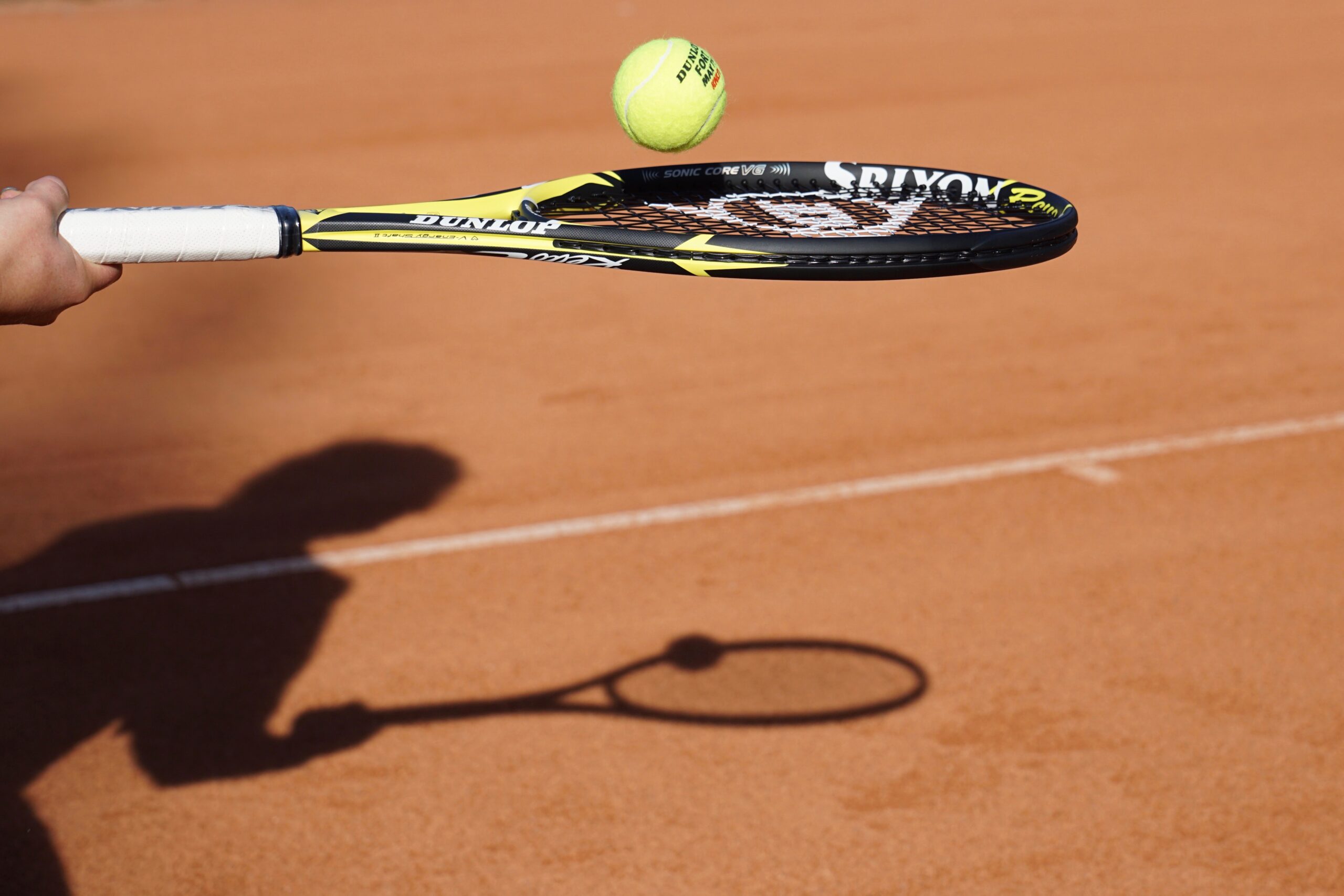 Tennisracket en tennisbal en schaduw van tennisspeler