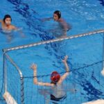 3 waterpolo spelers waarbij 1 speler de bal gaat gooien richting waterpolo doel