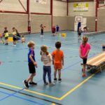 Meerdere kinderen die verschillende sportactiviteiten doen in een gymzaal